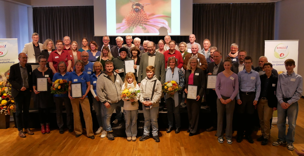 Auf einer Bühne im Festsaal des Alten Rathauses in Hannover stehen die Preisträgerinnen und Preisträger des Niedersächsichen Umweltpreises 2024. In der Mitte - Minister Meyer.